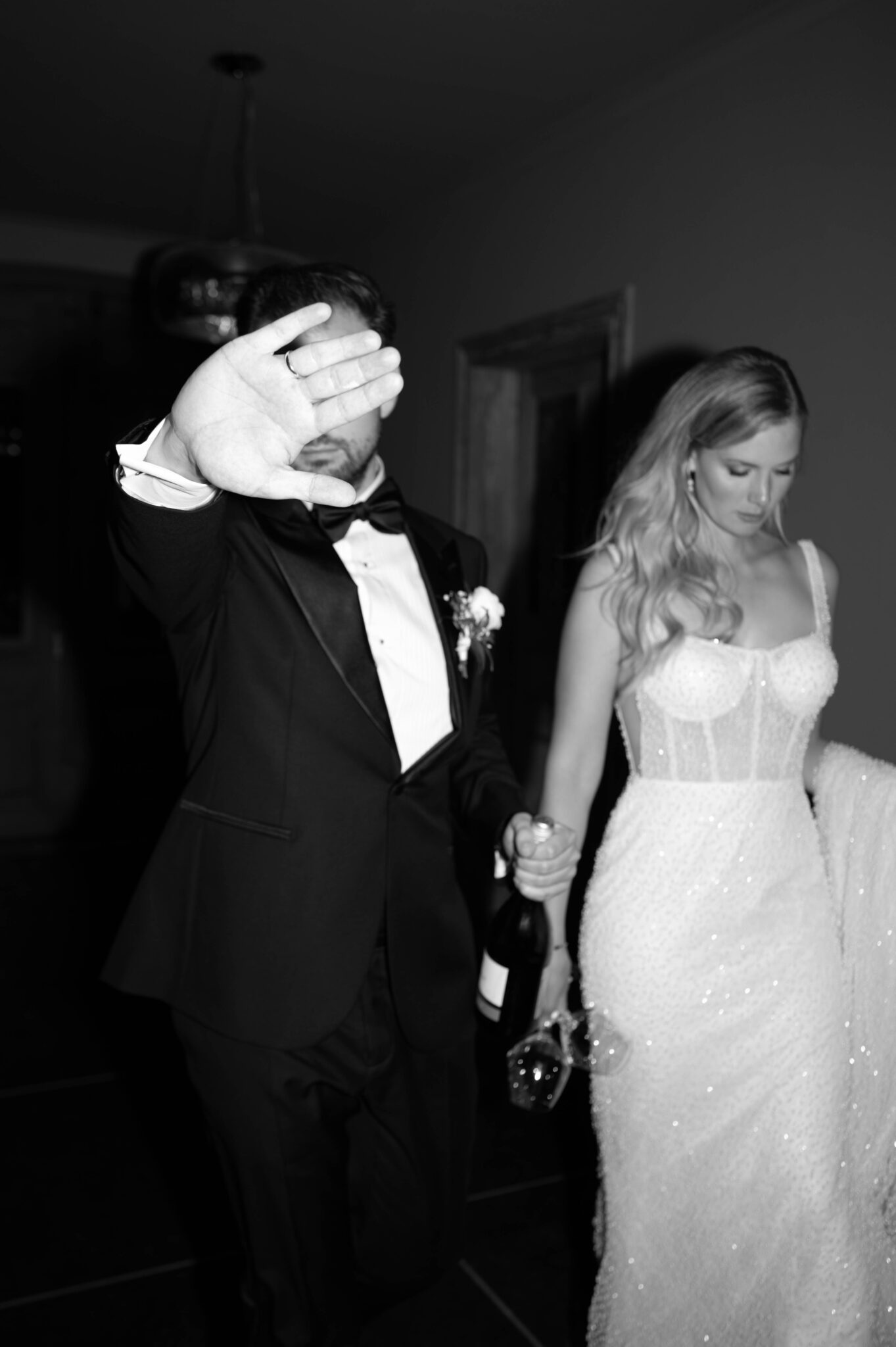 Ein Mann im Smoking blockiert die Kamera mit seiner Hand, während er mit einer Frau in einem weißen Kleid Händchen hält - und fängt damit die Aufregung einer von einem erfahrenen Hochzeitsplaner Italiens geplanten Hochzeit am Reiseziel ein.