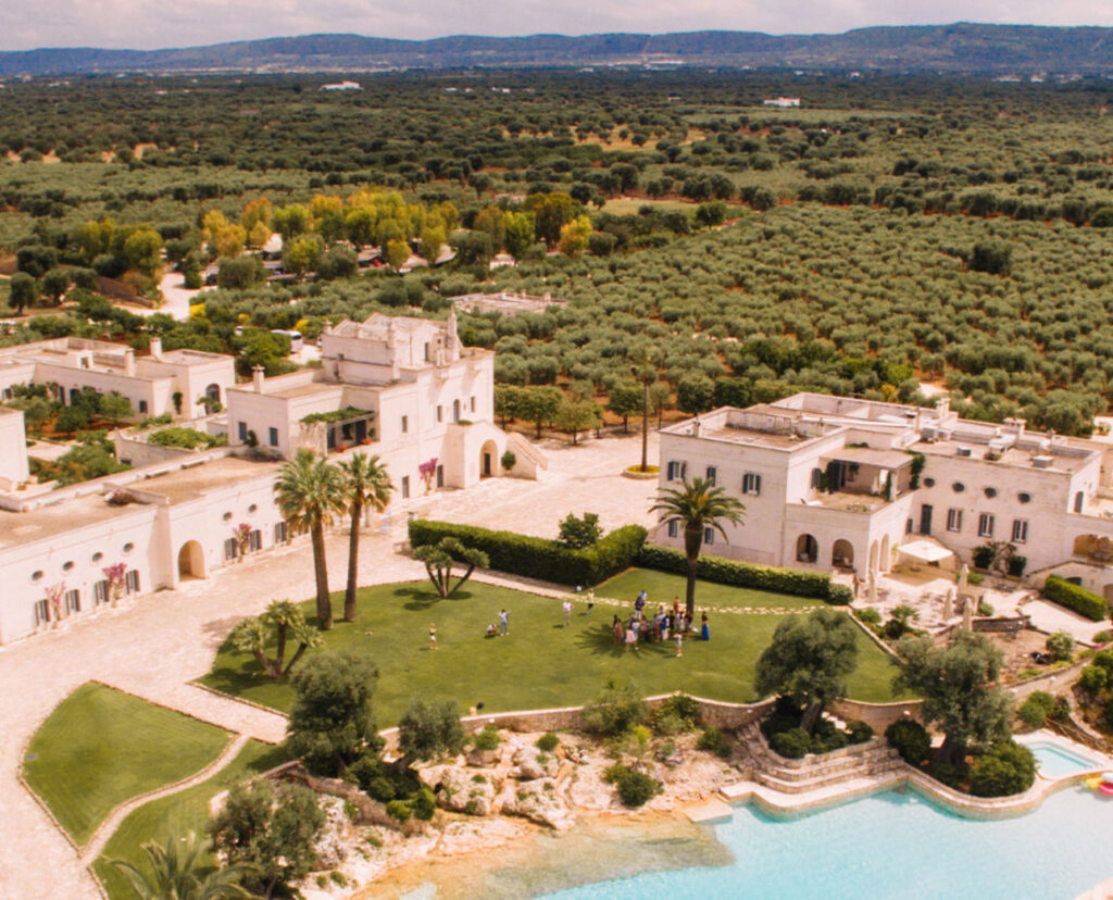 Ein großes weißes Gebäude mit einem Pool und Bäumen, perfekt für diejenigen, die vom Heiraten in Italien träumen oder das Know-how eines Hochzeitsplaners Italien suchen.