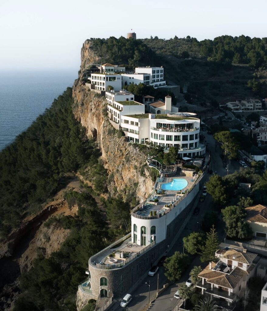 Ein luxuriöses Hotel auf einer Klippe mit Pools, direkt am Meer, umgeben von Bäumen und kurvenreichen Straßen – eine idyllische Lage auf Mallorca, perfekt für alle, die eine atemberaubende Kulisse und einen engagierten Hochzeitsplaner für ihren besonderen Tag suchen.
