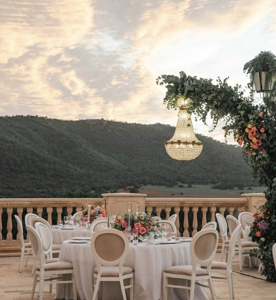 Elegante Tischdekoration im Freien bei Sonnenuntergang – eine ideale Hochzeitslocation auf Mallorca mit Blumendekoration und Kronleuchtern.