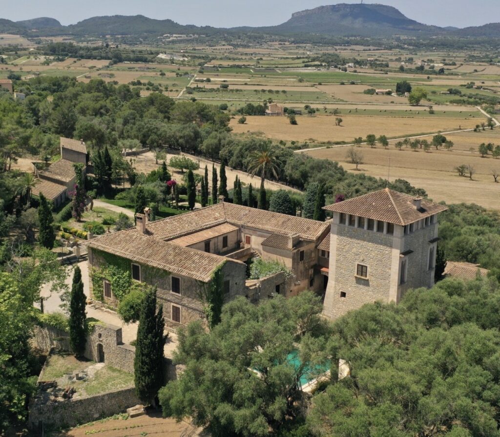 Luftaufnahme eines rustikalen Anwesens aus Stein auf Mallorca, umgeben von Feldern und Hügeln – der perfekte Ort für eine Hochzeit.