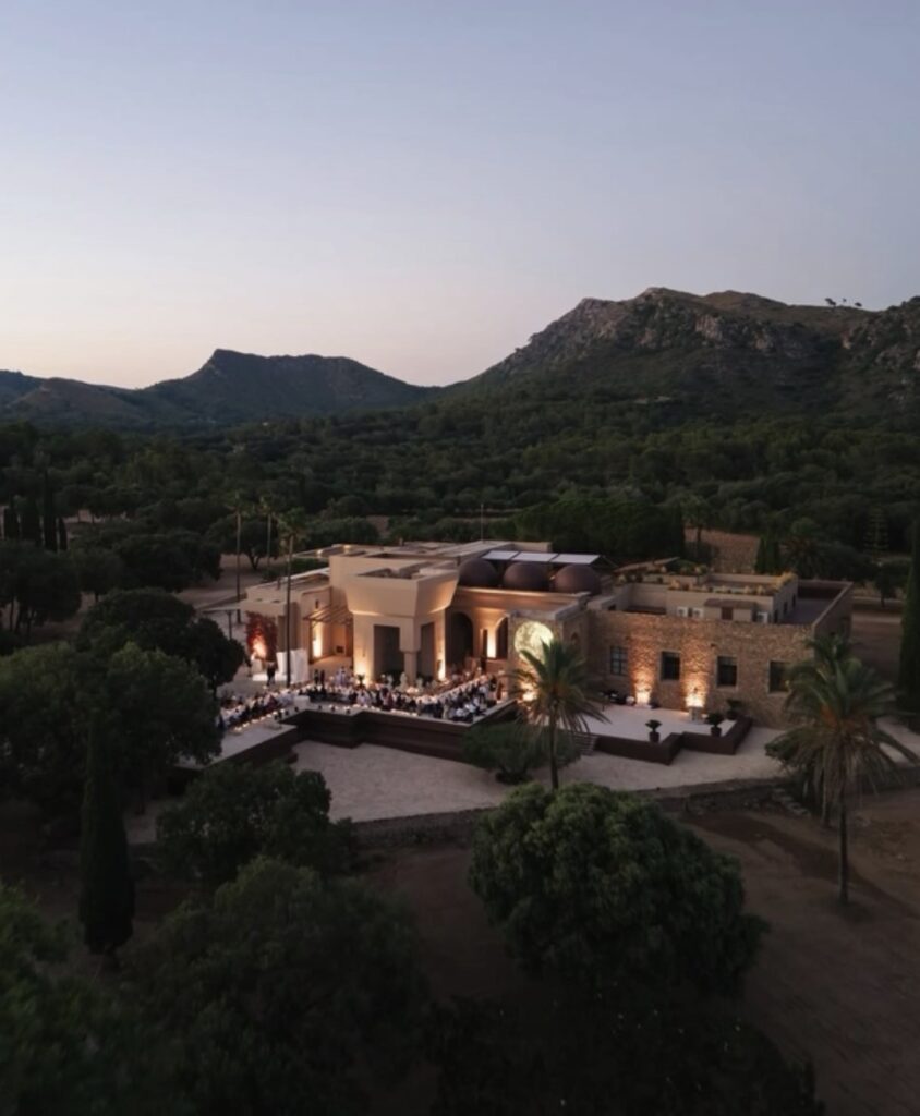 Eine moderne Villa auf Mallorca mit Außenbeleuchtung in der Abenddämmerung – ein perfekter Ort für eine Hochzeitsfeier, an dem die Gäste im Freien speisen können.