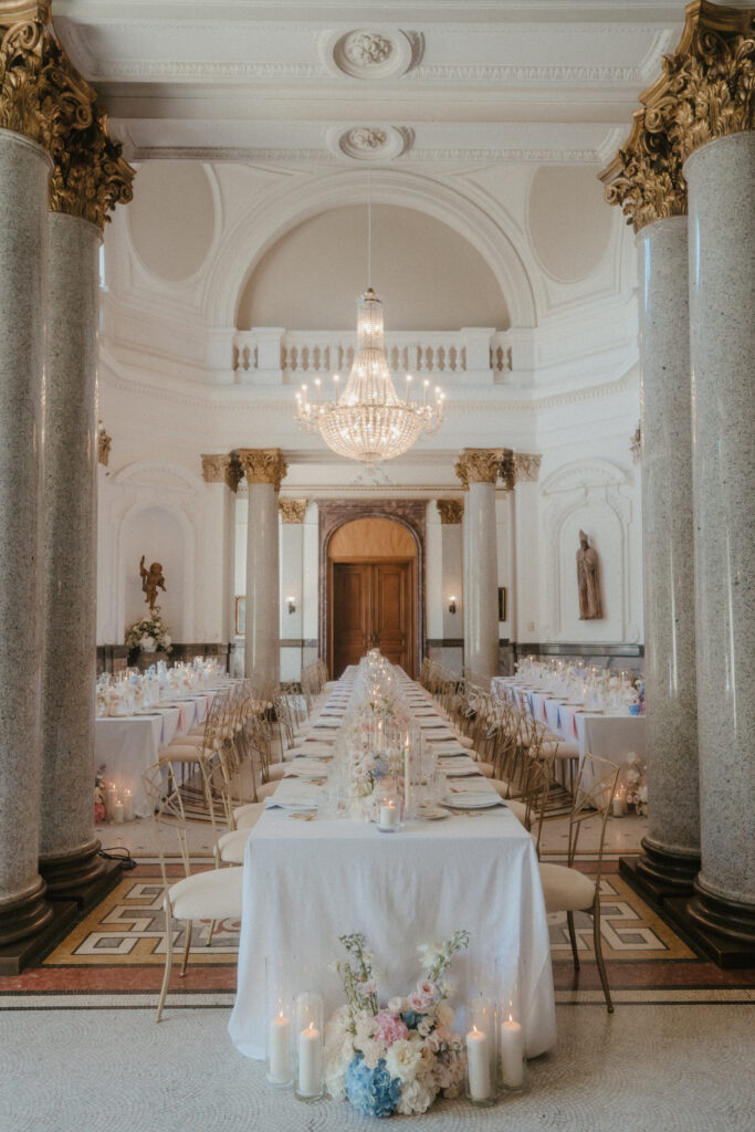 Eleganter Bankettsaal mit langen Tischen, goldenen Stühlen, Kronleuchtern und Blumenschmuck - perfekt für alle, die vom Heiraten in Italien träumen oder einen Top-Hochzeitsplaner Italien suchen, um eine unvergessliche Veranstaltung zu organisieren.