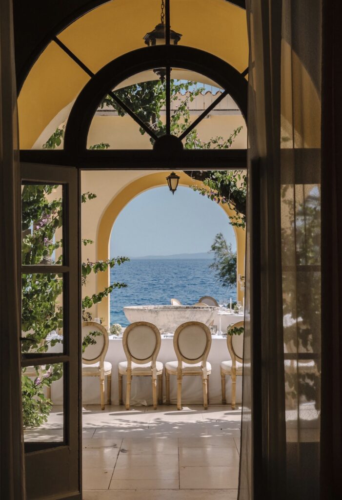 Der offene Torbogen der Villa Dalmacija mit seinen eleganten Stühlen und Bögen bietet einen Blick auf das blaue Meer unter klarem Himmel – eine idyllische Kulisse für „Heiraten am Meer“.
