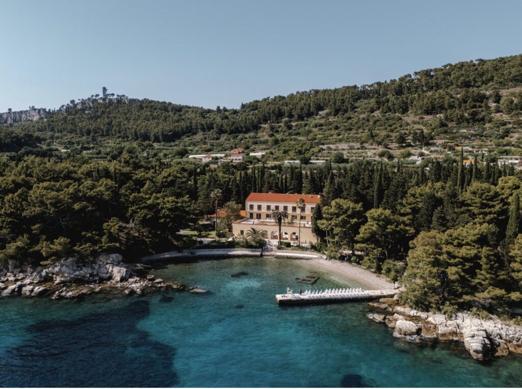 Luftaufnahme der Villa Dalmacija, einer atemberaubenden Villa am Meer mit rotem Dach, umgeben von Pinien und klarem, blauem Wasser – eine der bezauberndsten Hochzeitslocations, die Kroatien für Paare zu bieten hat, die davon träumen, am Meer zu heiraten.