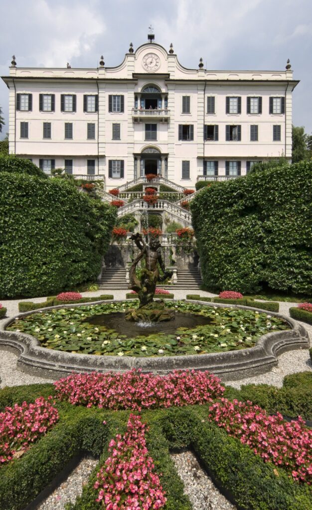 Eine prächtige weiße Villa mit einem Springbrunnen im Zentrum, üppigen Gärten und farbenprächtigen Blumen vor dem Haus – dieses atemberaubende Anwesen ist einer der begehrtesten Hochzeitsorte am Comer See und damit der perfekte Ort für eine luxuriöse Hochzeit im Ausland.