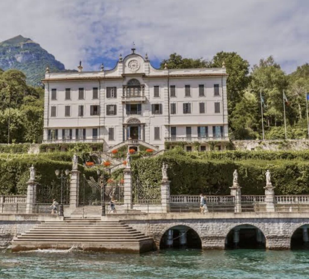 Eine prächtige Villa am Seeufer mit gewölbten Steganlagen, Statuen, gepflegten Hecken und den Bergen im Hintergrund – die ideale Wahl für eine luxuriöse Hochzeit im Ausland oder für alle, die nach exquisiten Hochzeitslocations für eine unvergessliche Hochzeit am Comer See suchen.