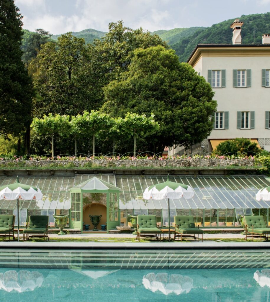 Ein gläserner Pavillon und grüne Stühle stehen am Pool, umrahmt von üppigen Bäumen und einer Villa im Hintergrund – eine idyllische Kulisse, die sich perfekt für eine luxuriöse Hochzeit im Ausland eignet oder für alle, die nach exklusiven Hochzeitslocations für ihre Hochzeit am Comer See suchen.
