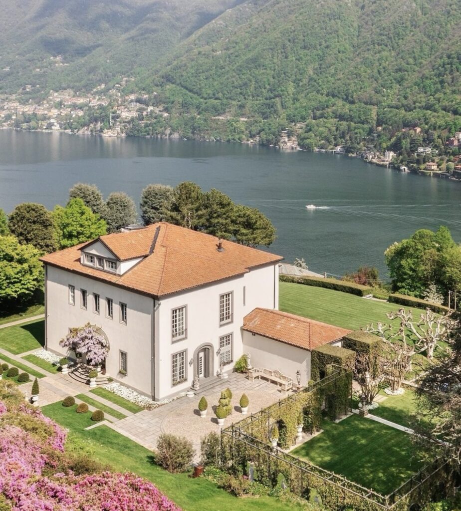 Eine großzügige Villa mit rotem Dach, gepflegten Gärten und Seeblick, umgeben von grünen Hügeln und blühenden Blumen – ein idealer Ort für eine luxuriöse Hochzeit am Comer See für alle, die von einer unvergesslichen Hochzeit inmitten atemberaubender Natur träumen.