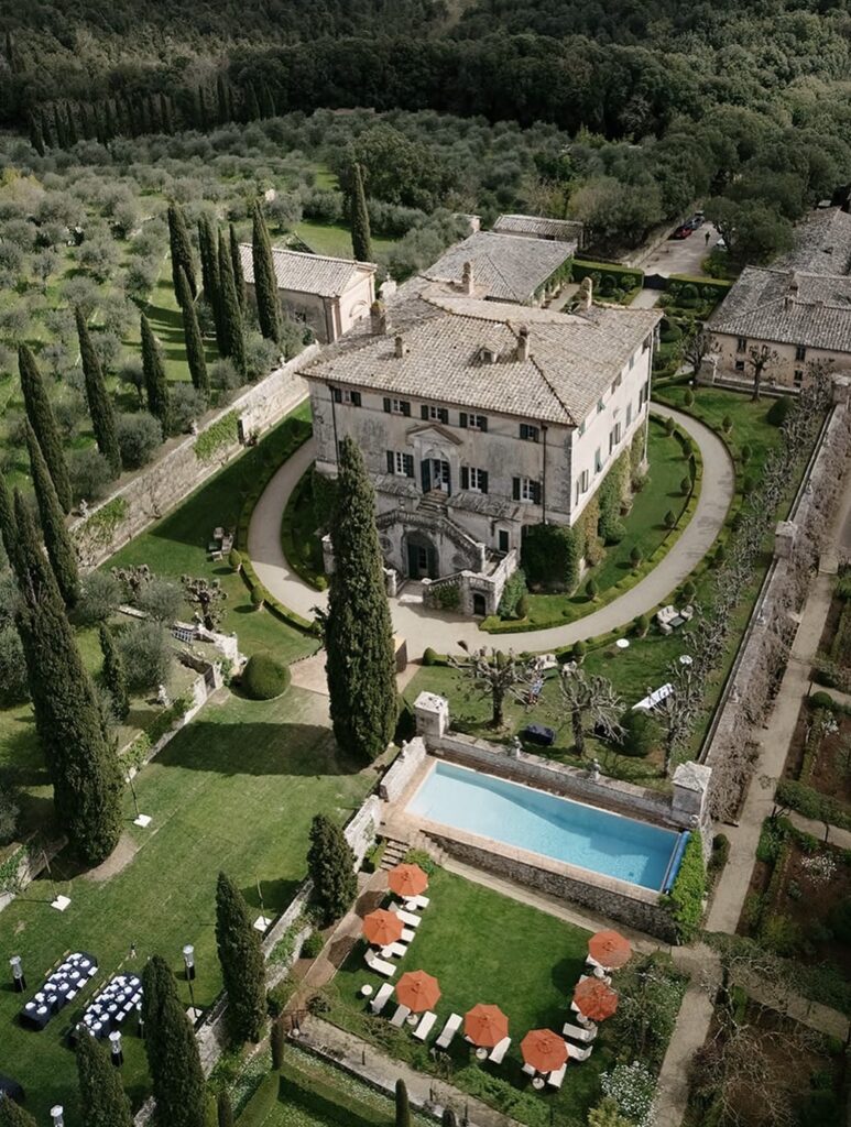 Luftaufnahme einer Villa mit Gärten, einem Pool, Liegestühlen und Bäumen inmitten einer grünen Landschaft – einer der schönsten Orte und eine ideale Wahl unter den Hochzeitslocations in der Toskana.