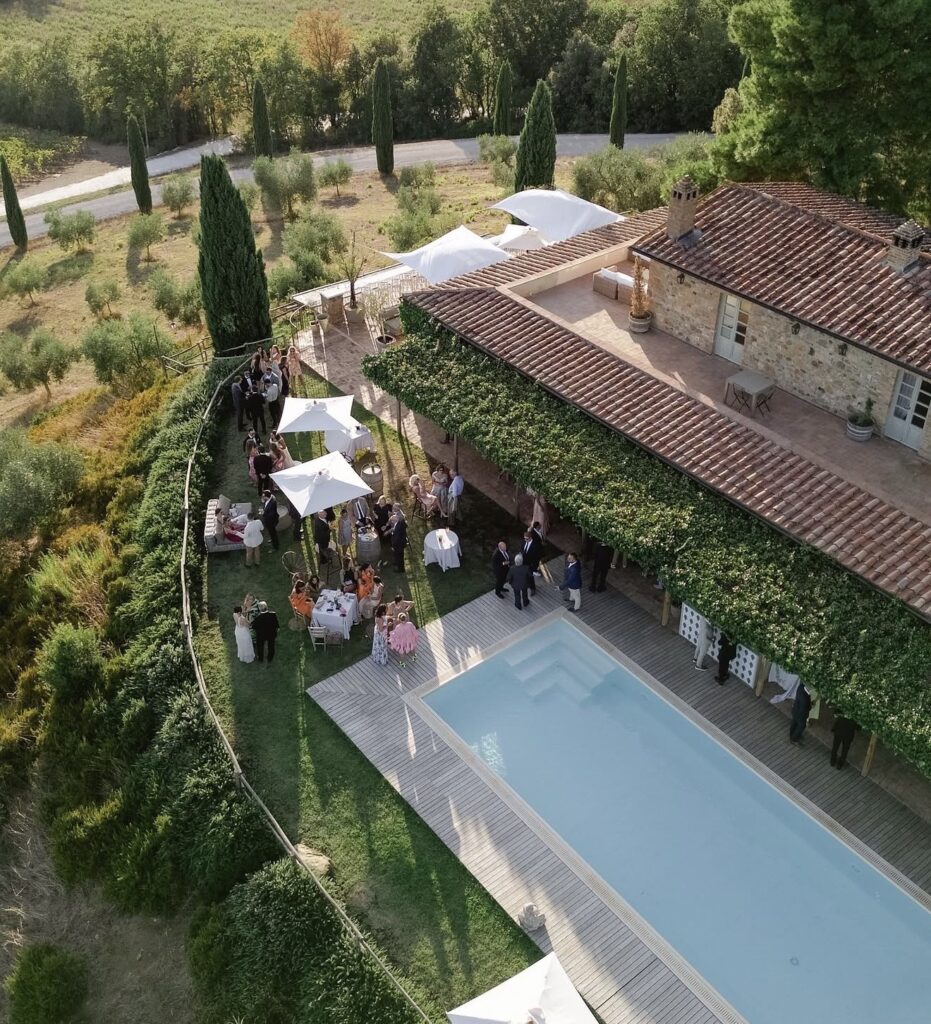 Luftaufnahme einer Feier im Freien am Pool einer rustikalen Villa, umgeben von Bäumen und viel Grün – einer der schönsten Orte und idealen Hochzeitslocations in der Toskana für eine unvergessliche Hochzeitsfeier in der Toskana.