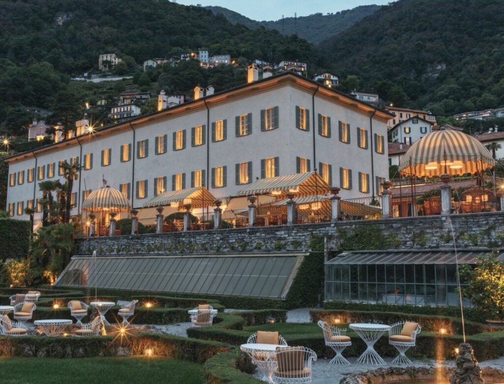 Elegant villa with striped awnings against the backdrop of the mountains in the evening twilight – perfect for a luxurious wedding near Lake Como.