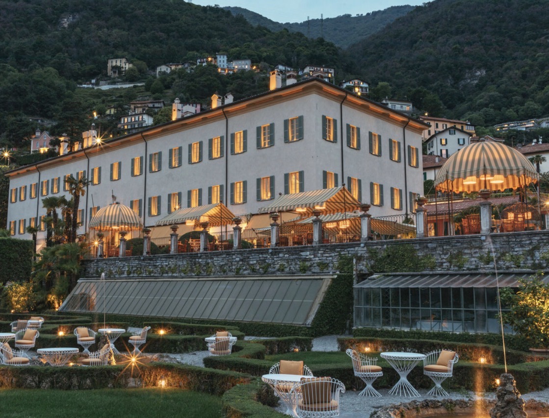 Elegant villa with striped awnings against the backdrop of the mountains in the evening twilight – perfect for a luxurious wedding near Lake Como.