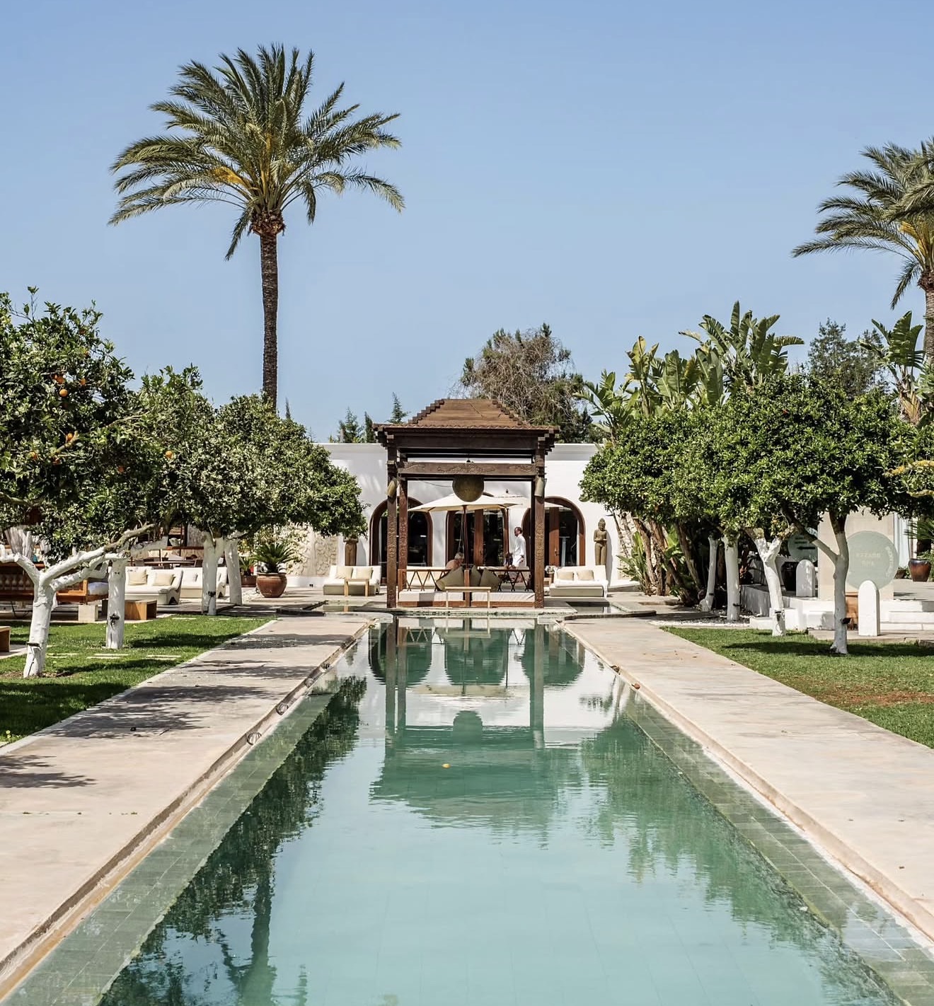 A long mirror pond leads to a terrace lined with orange trees at this luxurious wedding venue.