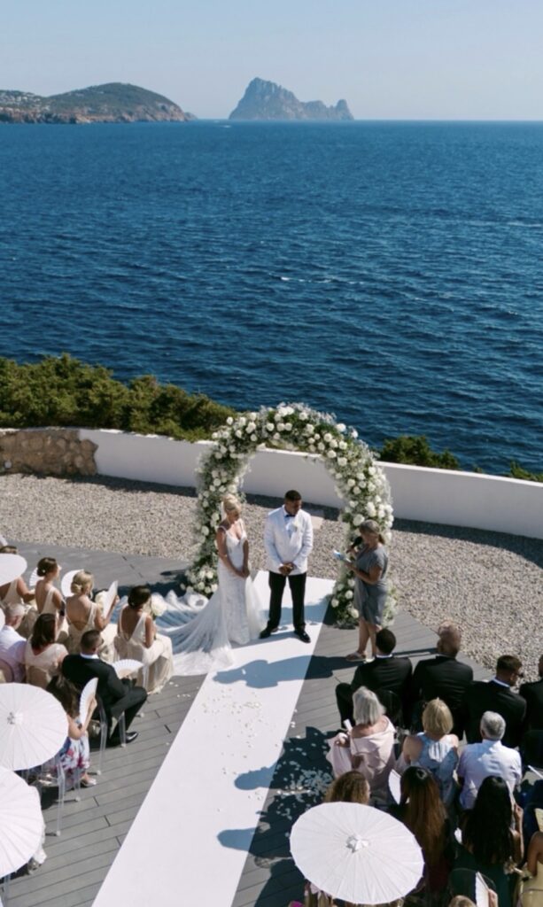 A couple gets married in a luxurious wedding ceremony under a floral arch in Ibiza.