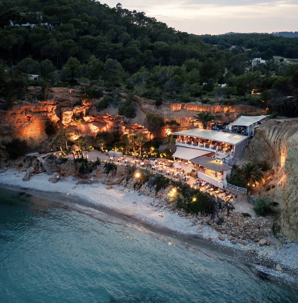 A beachfront restaurant lit up in the evening dusk and nestled on a rocky cliff – the perfect place for a luxurious wedding.